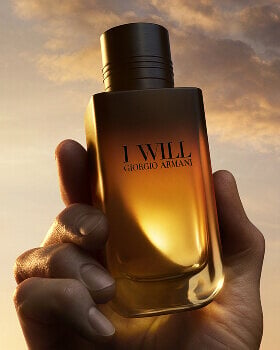 Giorgio Armani I WILL Eau de Parfum bottle held in hand. A refillable black-to-gold gradient design.