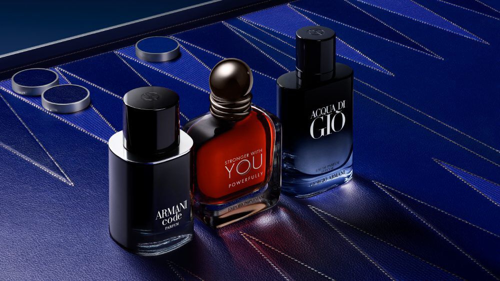 Armani Code, Stronger With You, and Acqua di Gio bottles displayed together on a textured blue surface, showcasing Armani’s iconic men’s fragrance collection.