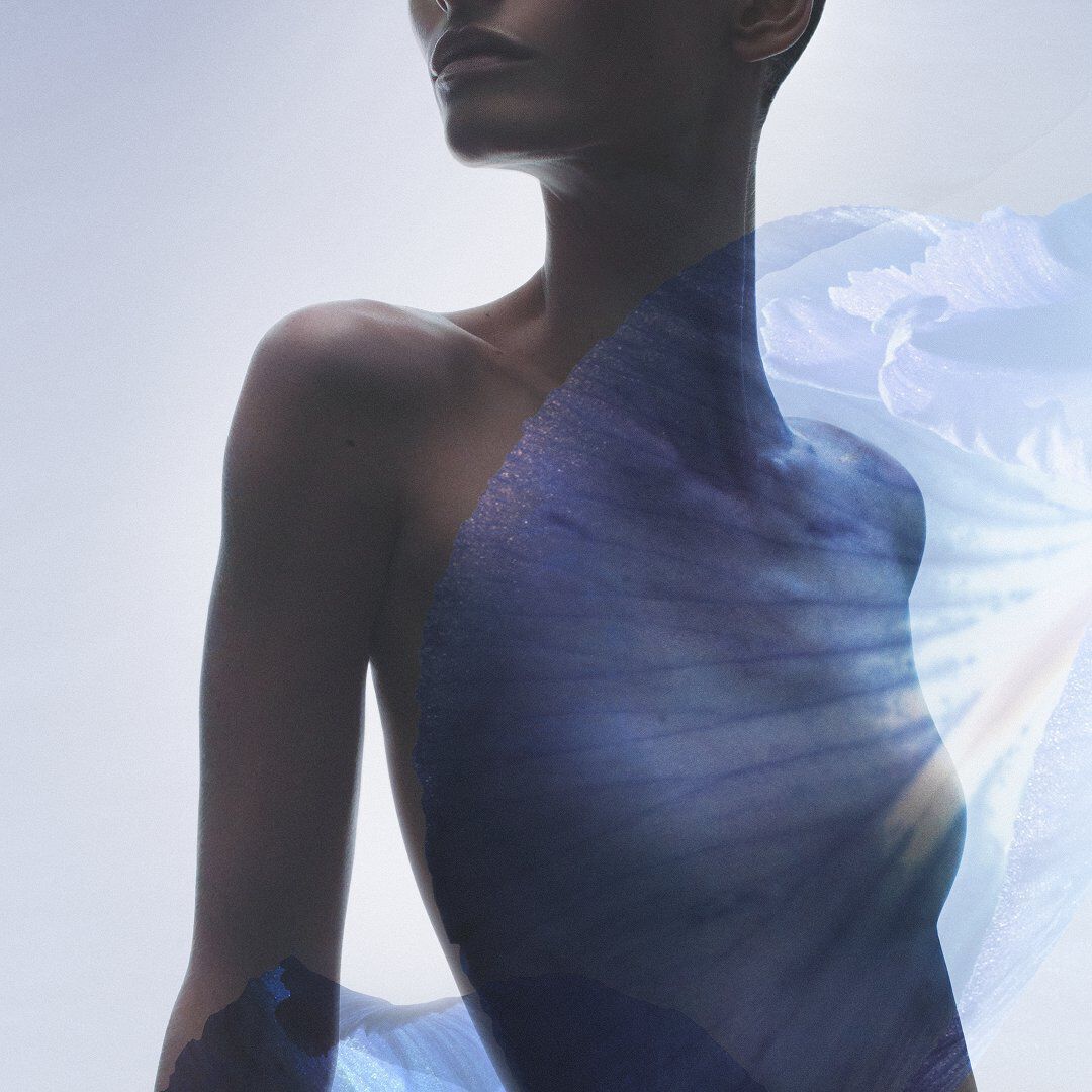 Cinematic silhouette of a man against a light warm background with woody and ambery ingredient overlays.