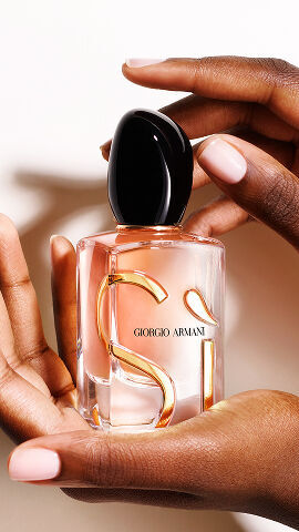 Hand holding the Giorgio Armani Si Eau de Parfum Intense on nude background.