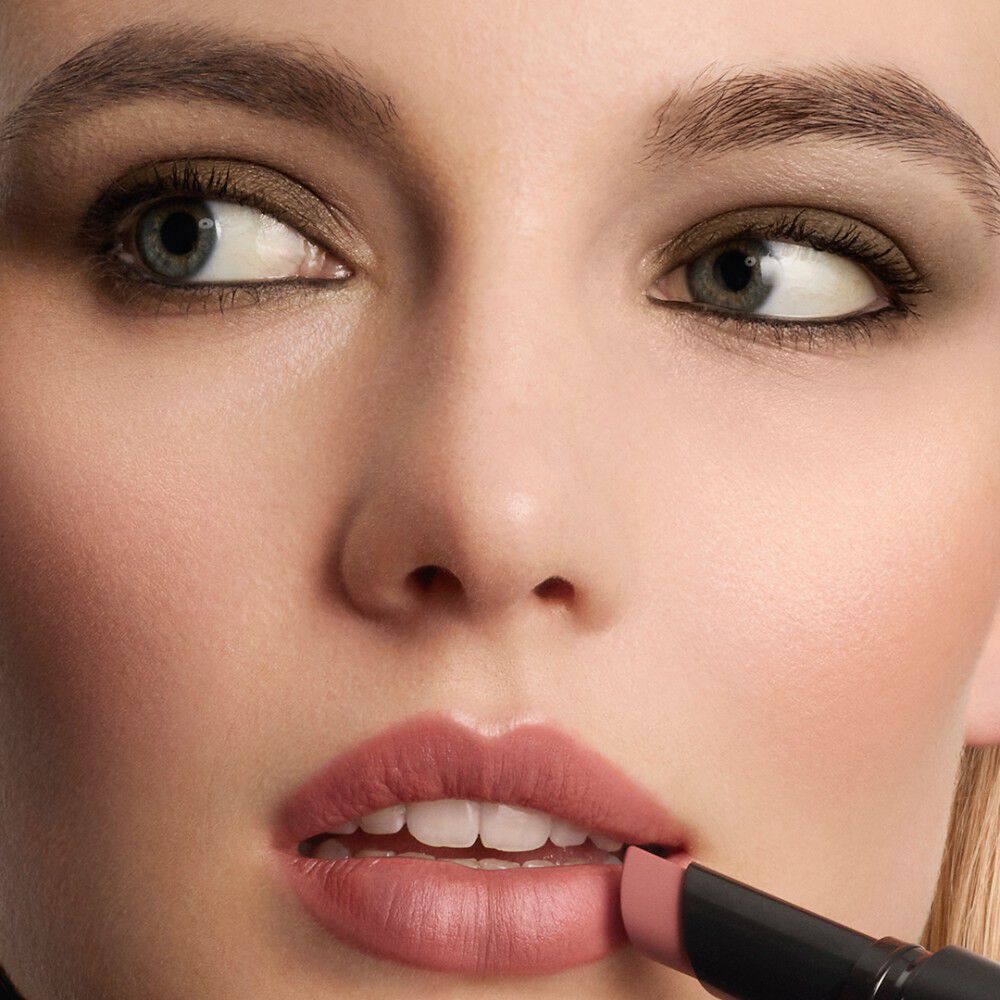A close-up of a woman's face as she applies a LIP POWER MATTE lipstick to her lips.