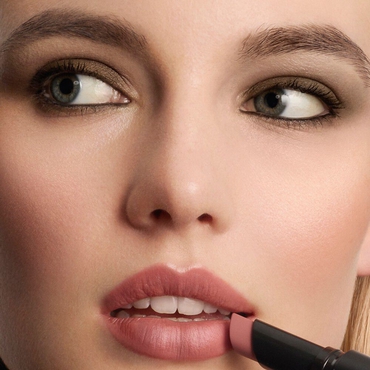A close-up of a woman's face as she applies a LIP POWER MATTE lipstick to her lips.