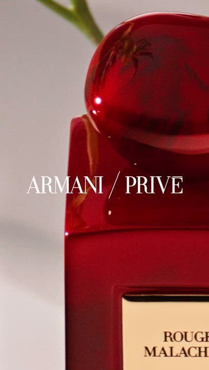 Armani/Prive fragrances: Rouge Malachite (red), Vert Malachite (green), Oud Nacre (white), and Magenta Tanzanite (magenta). Bottles with stone-like caps are displayed among raw stones and vibrant flowers.