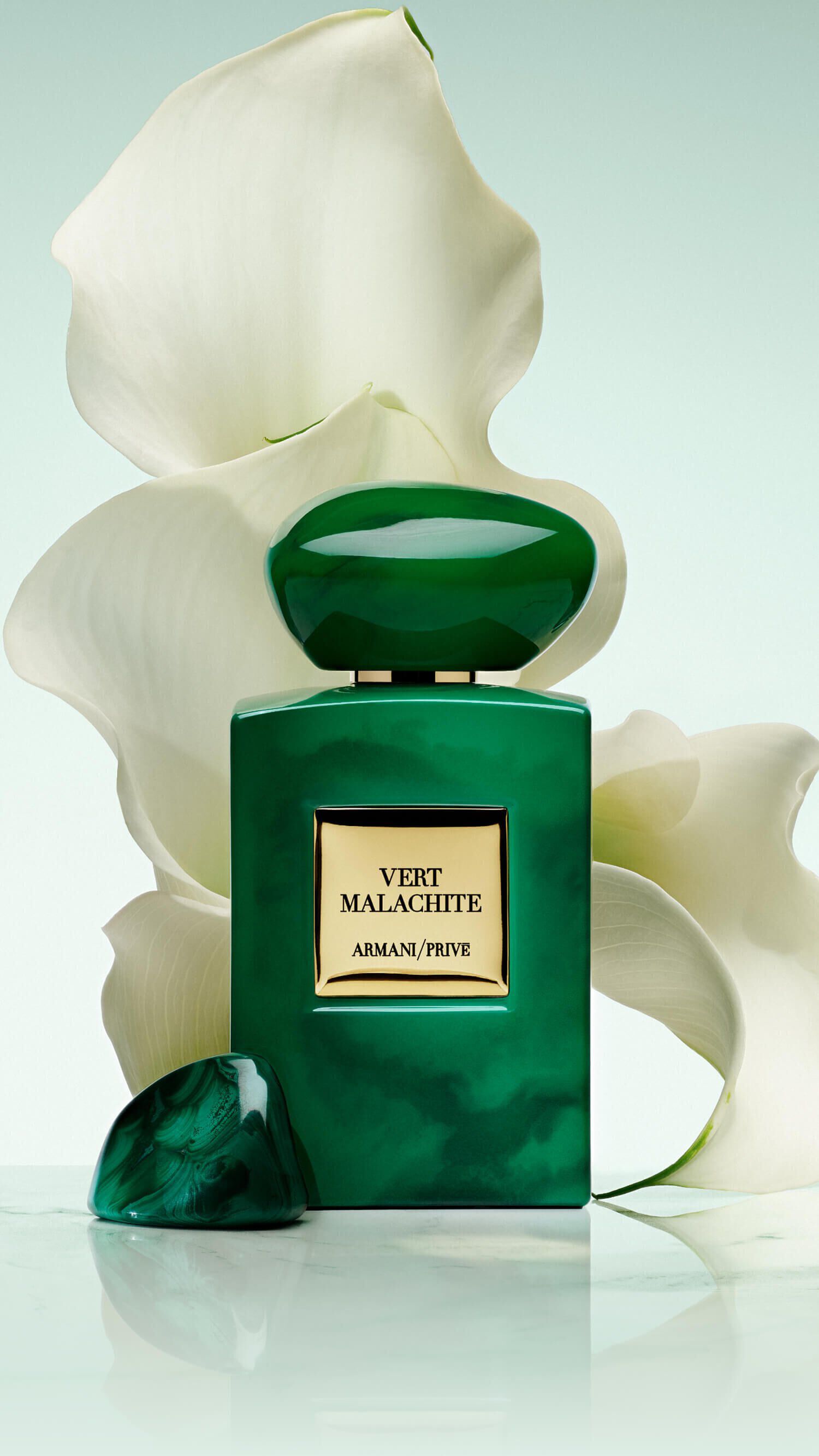 Bottle of Armani/Prive Vert Malachite against a light green background with opulent white flower. 
