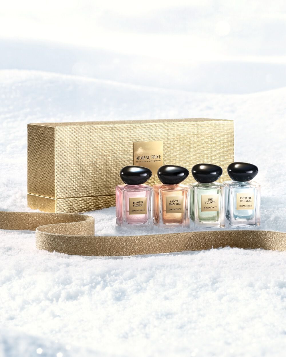 Armani/Prive Haute Couture fragrances in a golden coffret on snow for the holiday season.