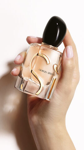 Hand holding the Giorgio Armani Si Eau de Parfum on nude background.