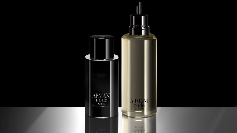 Side-by-side display of a full Armani Code Eau de Parfum bottle and a larger refill bottle. The refill bottle is transparent, revealing the pale yellow fragrance inside, and both have the Armani Code branding in white.