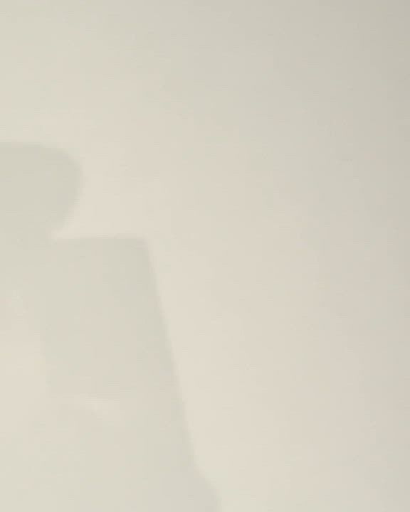 An artistic shadow of an Armani Prive fragrance bottle is cast against a light,