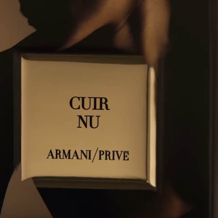 Cuir Nu hero video from Armani Prive showcases the fragrance bottle elegantly set against an Italian leather-inspired backdrop, featuring a silhouetted male model. The bottle is consistently displayed with sculptural leather fabric, effectively illustrating the olfactive inspiration behind the scent. Further enriching this visual narrative are a sculptural botanical element that evokes the refined power of oud, and a golden-toned roasted coffee bean representing one of Cuir Nu’s sensual notes. These elements are part of the broader Armani/Prive Les Mille et Une Nuits collection, characterized by fragrance bottles adorned with rich golden oud textures.