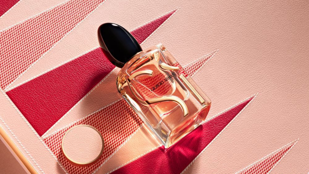 Armani Si Eau de Parfum bottle and cap from the Mother’s Day gift set on a pink and red geometric backgammon background.