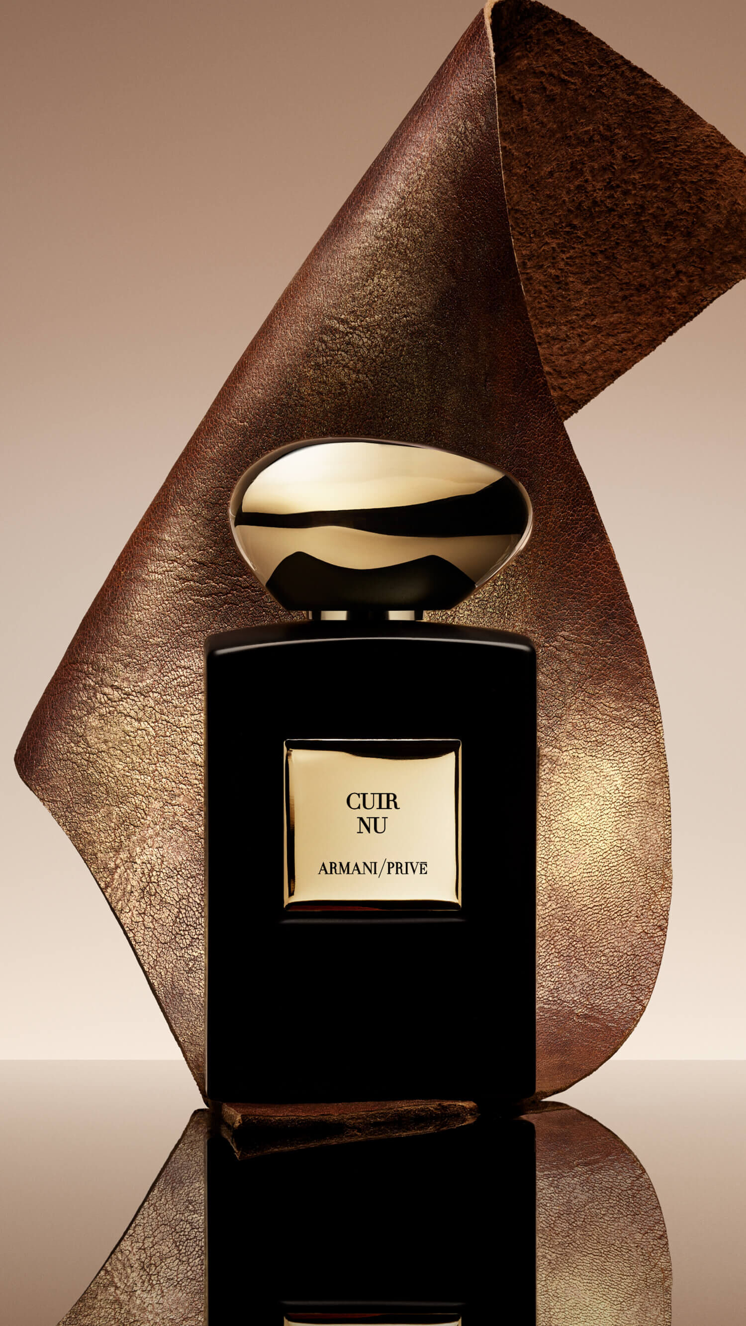Bottle of Armani/Prive Cuir Nu against a light brown backrgound with ambery ingredient. 