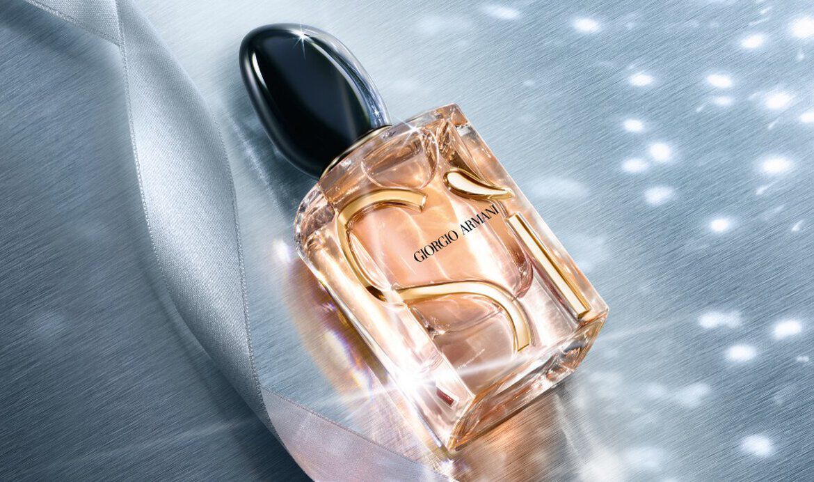 Giorgio Armani Si Eau de Parfum perfume bottles styled on a blue fabric background with sparkling light effects