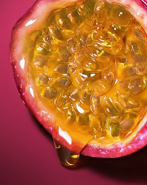 Close-up of Maracuja (Passion Fruit) glistening with golden juice, illustrating the vibrant top note of the Armani Power of You fragrance.