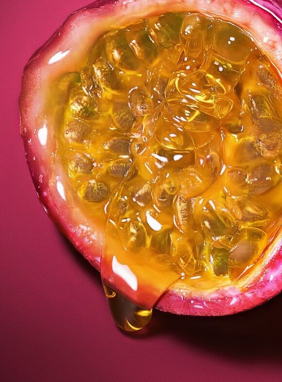Close-up of Maracuja (Passion Fruit) glistening with golden juice, illustrating the vibrant top note of the Armani Power of You fragrance.