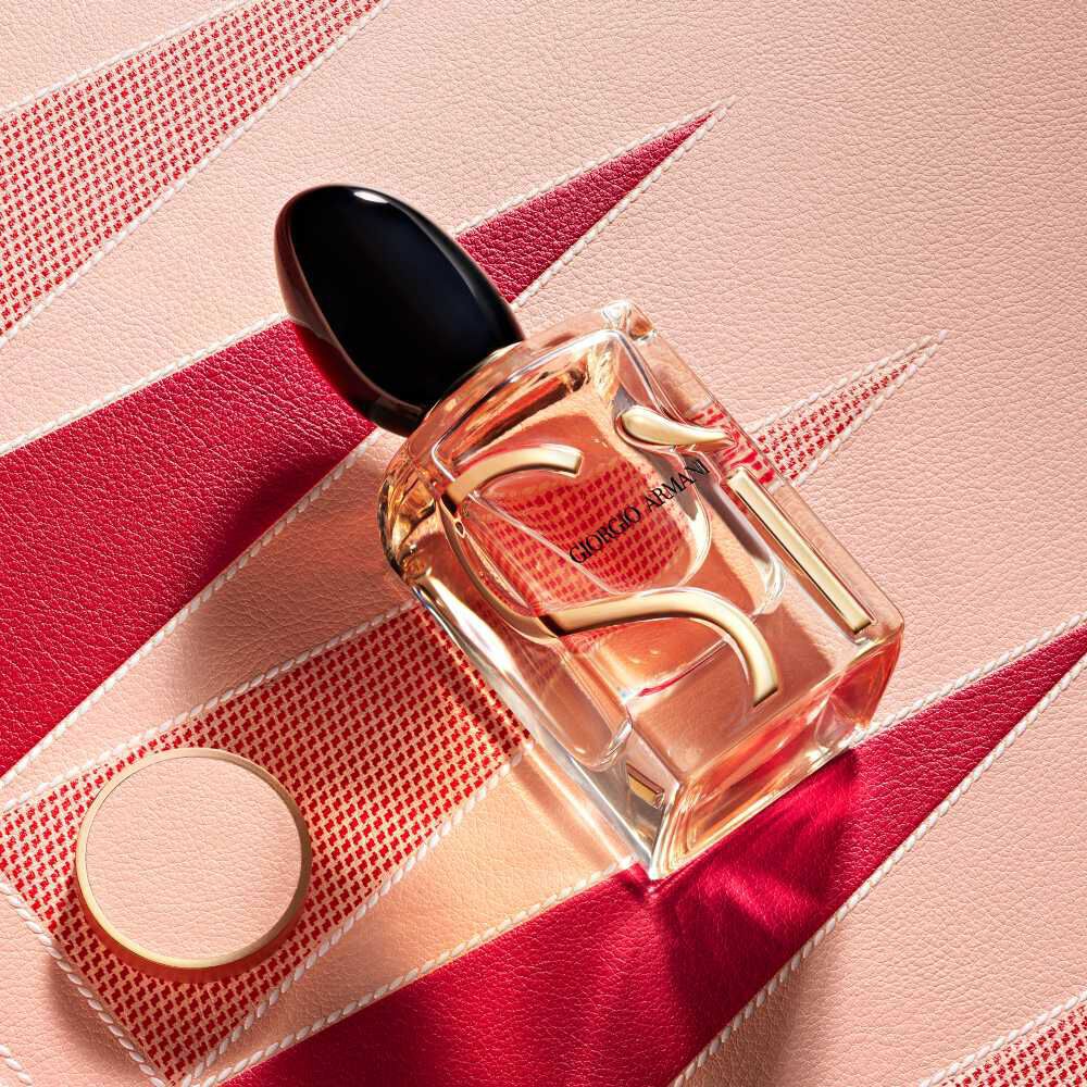 Armani Si Eau de Parfum bottle and cap from the Mother’s Day gift set on a pink and red geometric backgammon background.