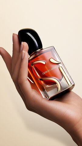Hand holding the Giorgio Armani Si Parfum Intense on nude background.
