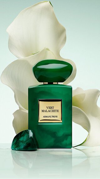 Bottle of Armani/Prive Vert Malachite against a light green background with a white flower.