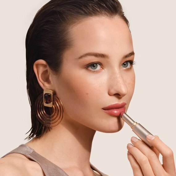 Model applying Prisma Flash glossy lip balm by Giorgio Armani Beauty, showcasing glossy shine, vibrant colour and hydrating comfort