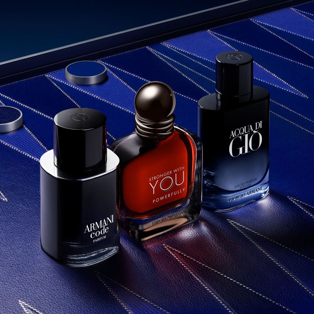 Armani Code, Stronger With You, and Acqua di Gio bottles displayed together on a textured blue surface, showcasing Armani’s iconic men’s fragrance collection.