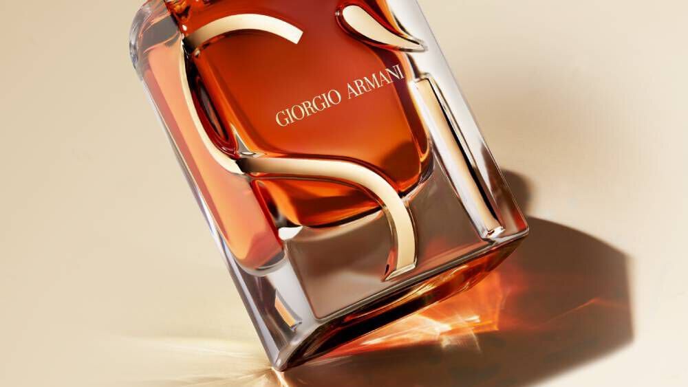 Close-up of a single Giorgio Armani Si perfume bottle, showcasing its amber liquid and the sculpted "Si" design on the glass.
