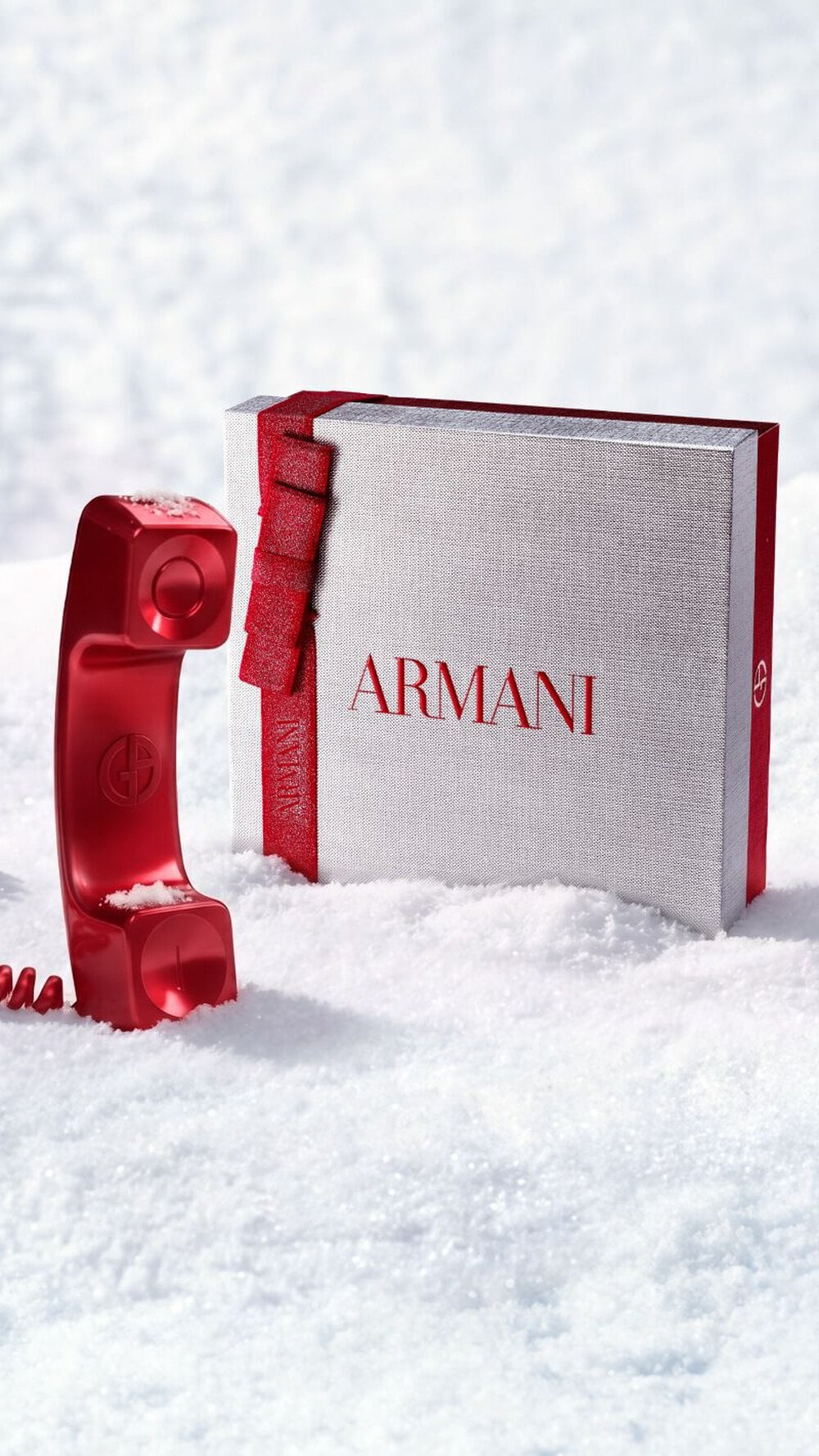 Armani beauty holiday gift box with red client services phone in a snowy setting.