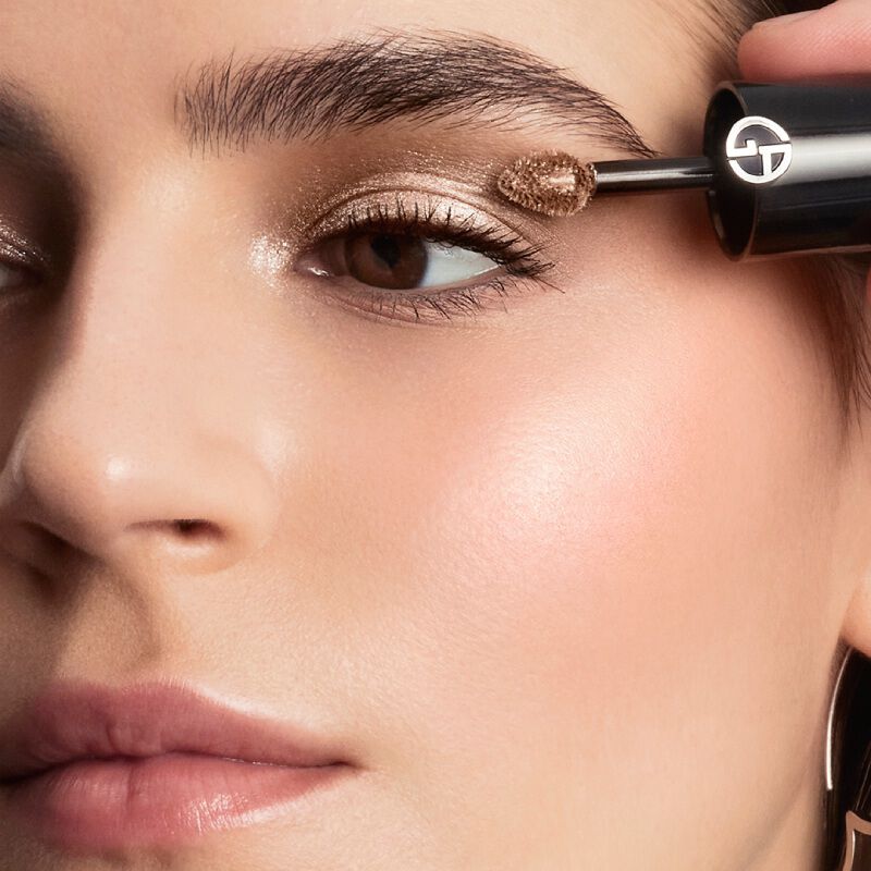 A model's face with two shades of liquid foundation or concealer applied in V-shapes on their cheek and jawline.