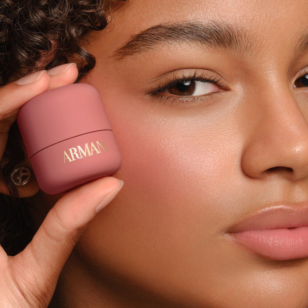 Model holding pink Armani Beauty Dolci Blush, a cream-to-powder blush with a natural finish.