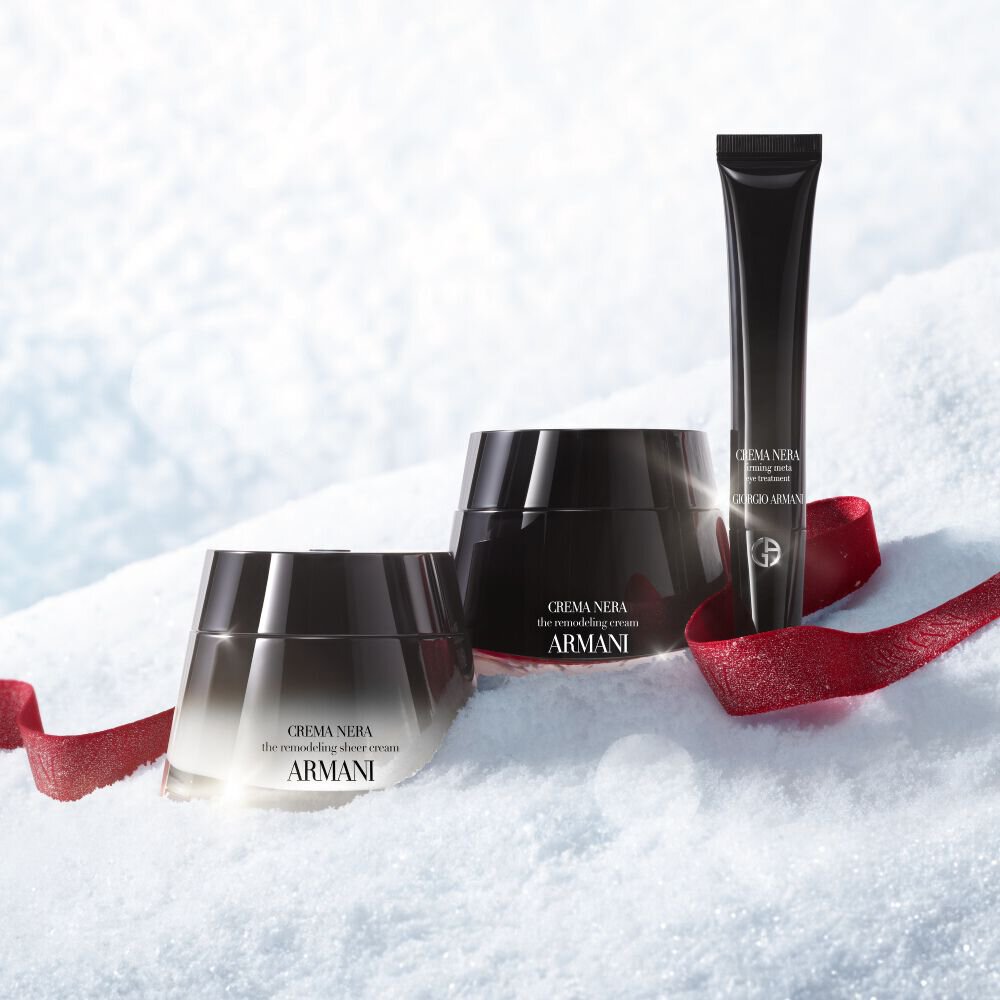 Armani beauty Crema Nera skincare products on snow with a red ribbon.