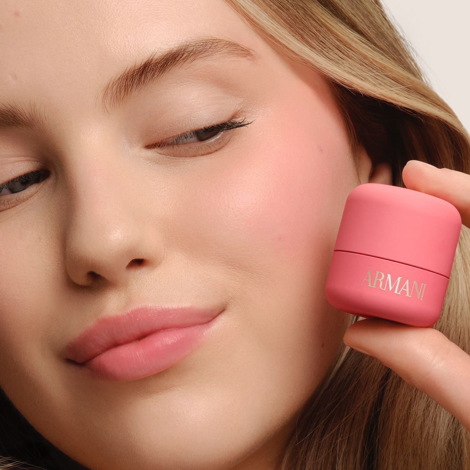 Model holding ARMANI Beauty DOLCI blush near her cheek, showing a fresh pink blush result