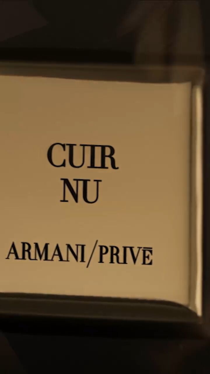 Cuir Nu hero video from Armani Prive showcases the fragrance bottle elegantly set against an Italian leather-inspired backdrop, featuring a silhouetted male model. The bottle is consistently displayed with sculptural leather fabric, effectively illustrating the olfactive inspiration behind the scent. Further enriching this visual narrative are a sculptural botanical element that evokes the refined power of oud, and a golden-toned roasted coffee bean representing one of Cuir Nu’s sensual notes. These elements are part of the broader Armani/Prive Les Mille et Une Nuits collection, characterized by fragrance bottles adorned with rich golden oud textures.