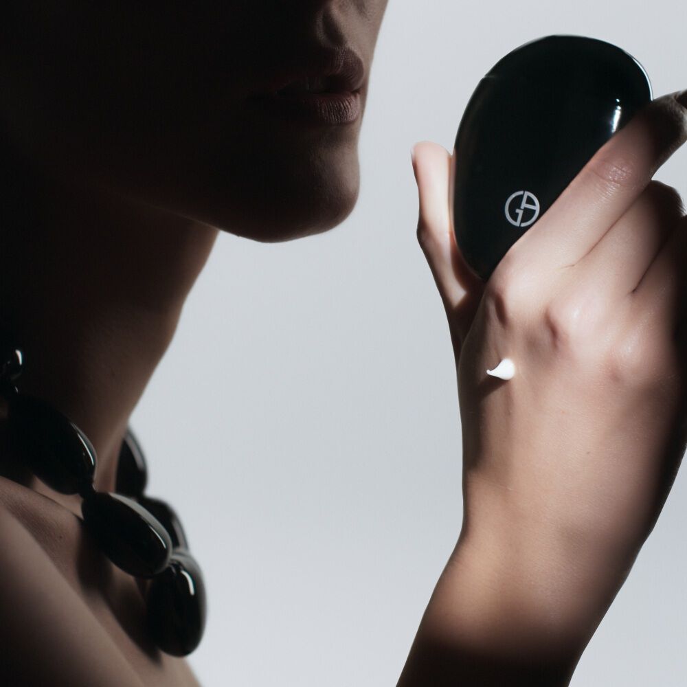 Woman holding Armani beauty THE HAND CREAM while demonstrating the hand care application ritual.