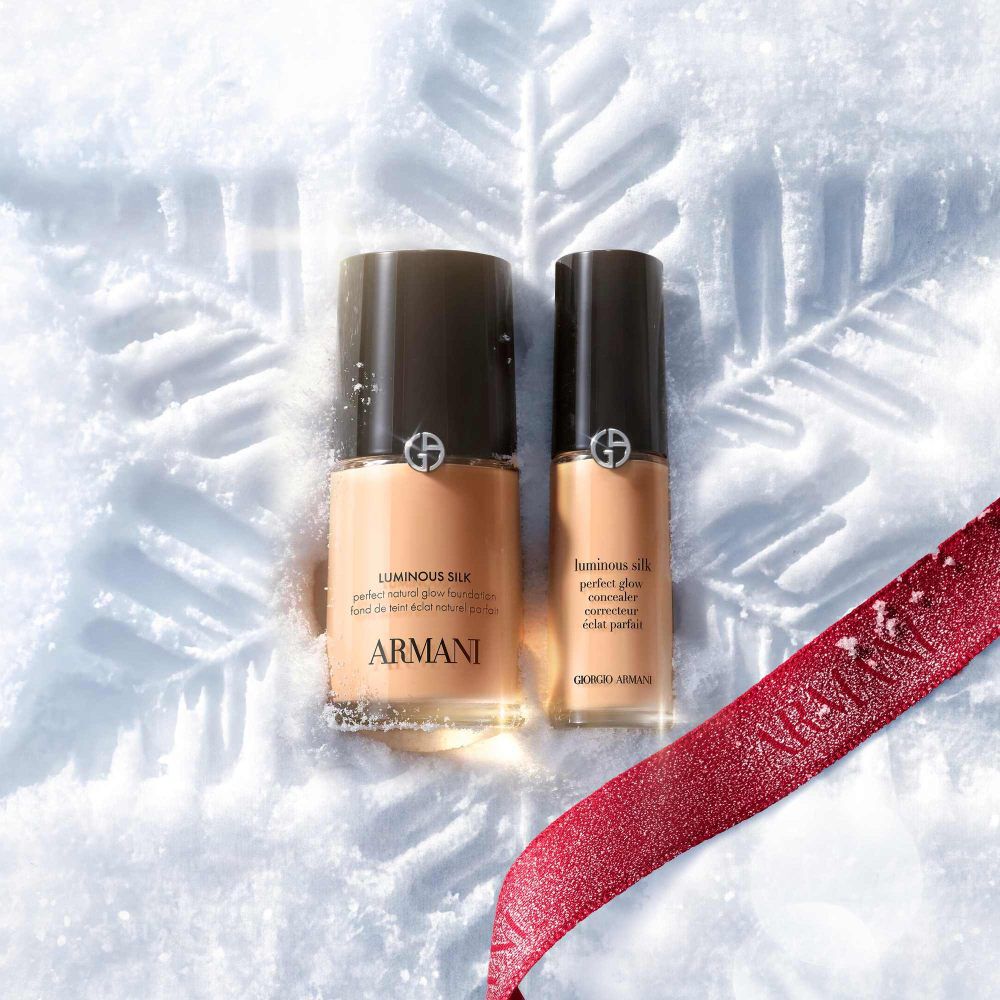 Armani beauty Luminous Silk Foundation and Concealer in shade 5.5, set on pristine snow with a deep red silk ribbon. Holiday 2026 product family visual.