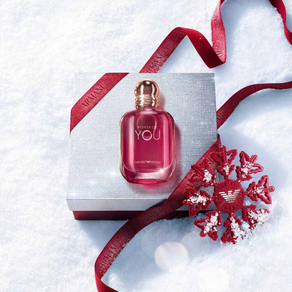 Ruby Power of You Eau de Parfum bottle with red Armani ribbon and jewelled snowflake on a snowy surface — Giorgio Armani women's fragrance, holiday gift set visual.