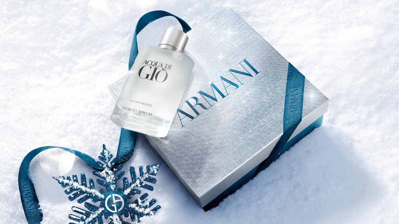 Acqua di Gio Eau de Toilette 50ml gift set in a silver Armani gift box with blue ibbon, styled on a snowy surface with a blue glitter snowflake — Giorgio Armani holiday fragrance gift for men.