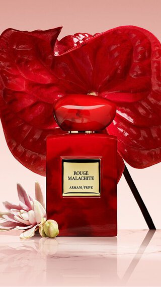 Bottle of Armani/Prive Rouge Malachite against a light red background with a opulent red flower.