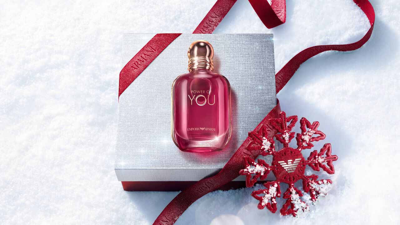 Ruby Power of You Eau de Parfum bottle with red Armani ribbon and jewelled snowflake on a snowy surface — Giorgio Armani women's fragrance, holiday gift set visual.