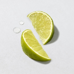 Lime slices and sea salt crystals on a light grey background — marine notes and bergamot, top notes of Acqua di Gio Eau de Toilette by Giorgio Armani.