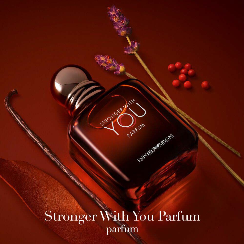 Emporio Armani Stronger With You Parfum — 100ml deep red bottle surrounded by key olfactive ingredients: lavender, pink pepper, vanilla, and leather accord on a rich amber background.