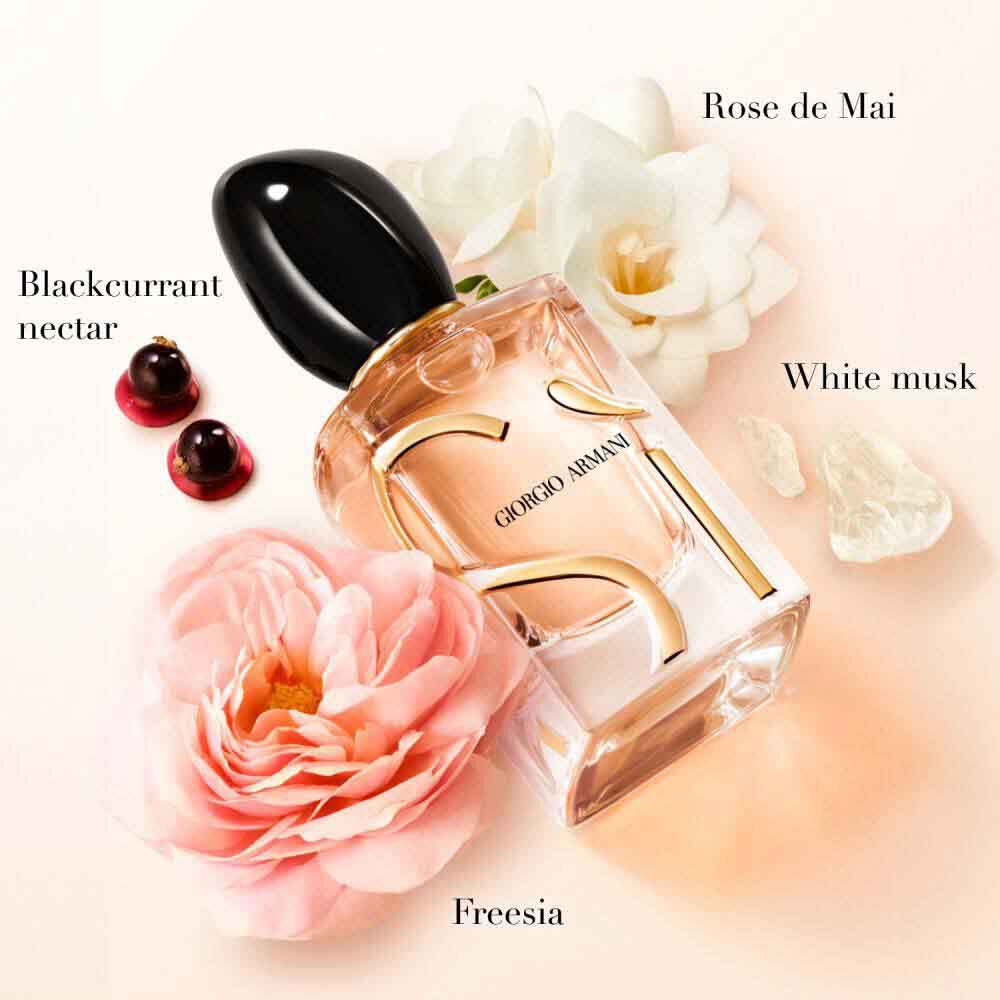 Si Eau de Parfum bottle surrounded by rose de mai, blackcurrant, freesia and white musks ingredient blooms on a soft blush background — Giorgio Armani women's floral fragrance key notes visual.