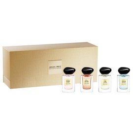 Armani Prive Les Eaux Holiday gift set on white background: gold rectangular box with four miniature eau de parfum bottles with black caps arranged beside it.