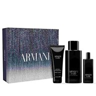 A boxed Armani Code gift set is displayed, featuring a stylish, dark blue box with a gradient design and the Armani logo. In front of the box are three products: a tube of body gel, a large bottle of Eau de Toilette, and a smaller travel-size Eau de Toilette, all in sleek black packaging.