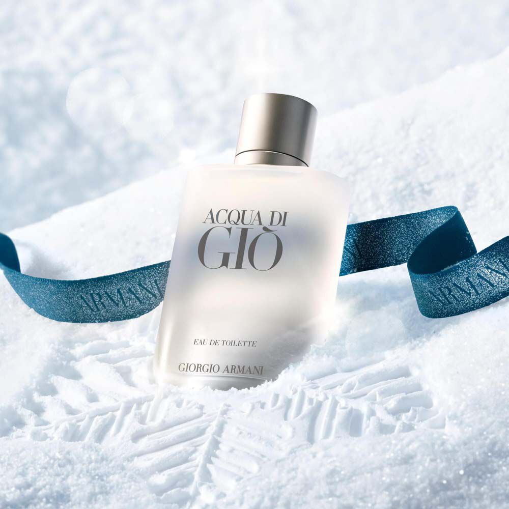 Acqua di Gio Eau de Toilette by Giorgio Armani, clear glass bottle resting in snow with a blue Armani ribbon — men's aquatic fragrance, holiday gifting visual.
