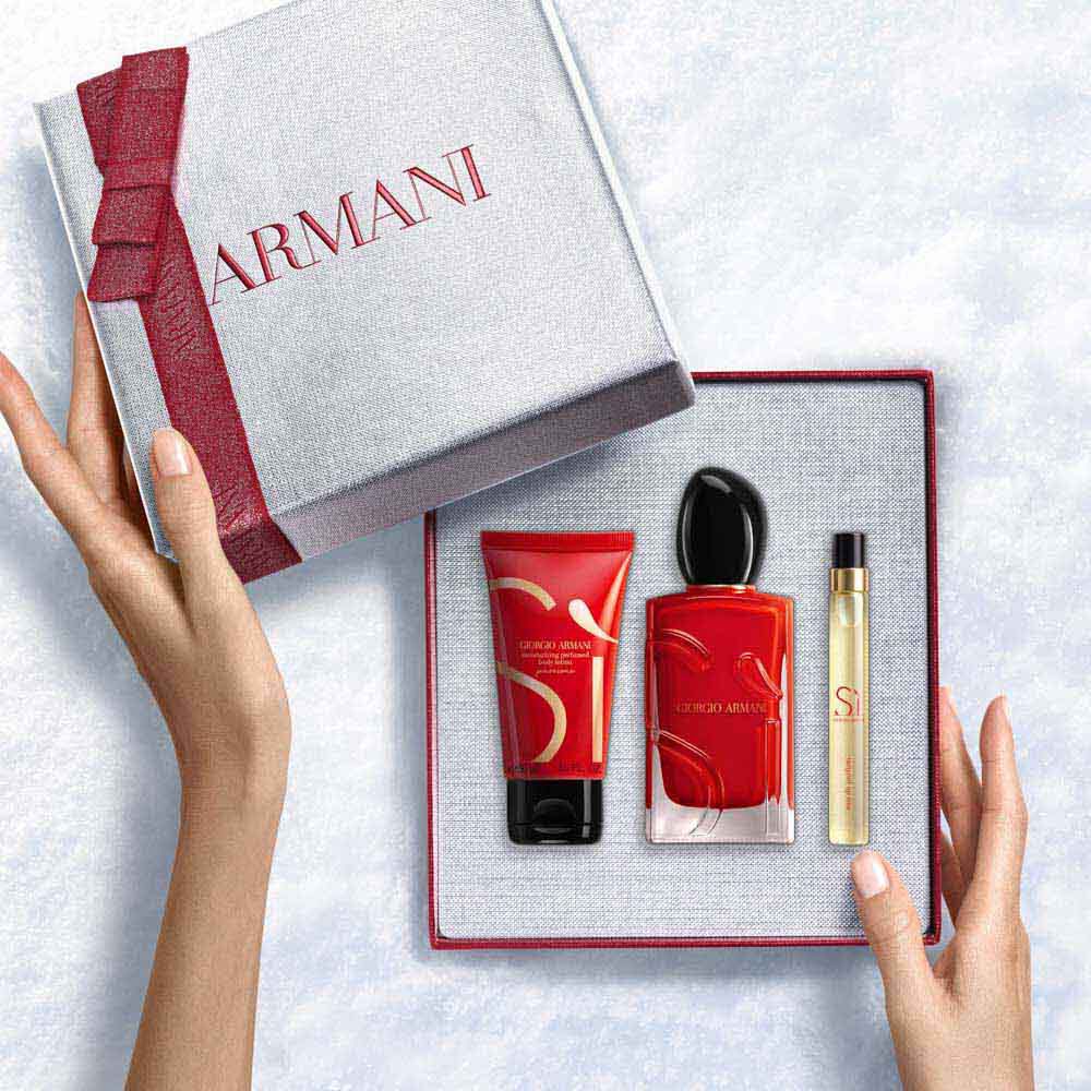 Hands unveiling a red-ribboned white Armani gift box withSi Passione Eau de Parfum 100ml, 10ml travel size and 50ml Perfumed Body Lotion — a bold women's floral fragrance gift set