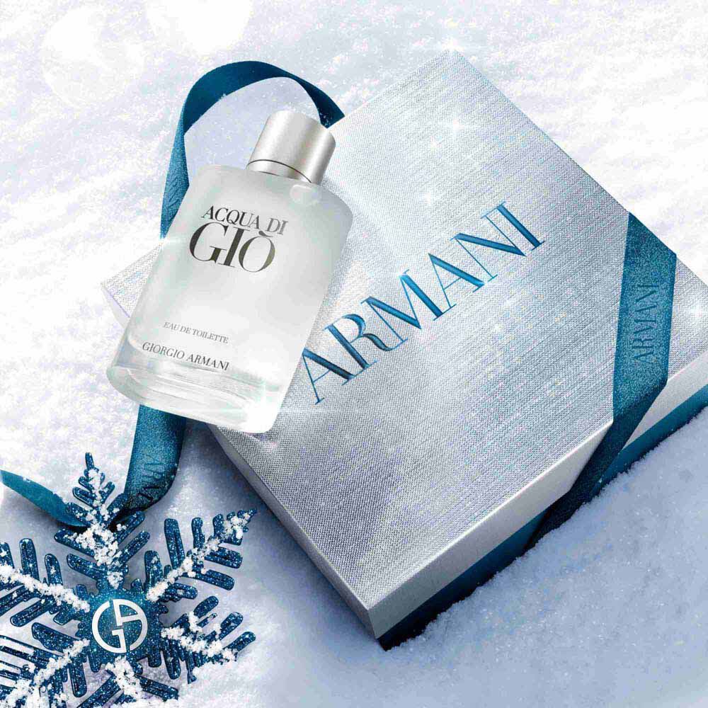 Acqua di Gio Eau de Toilette 50ml gift set in a silver Armani gift box with blue ibbon, styled on a snowy surface with a blue glitter snowflake — Giorgio Armani holiday fragrance gift for men.