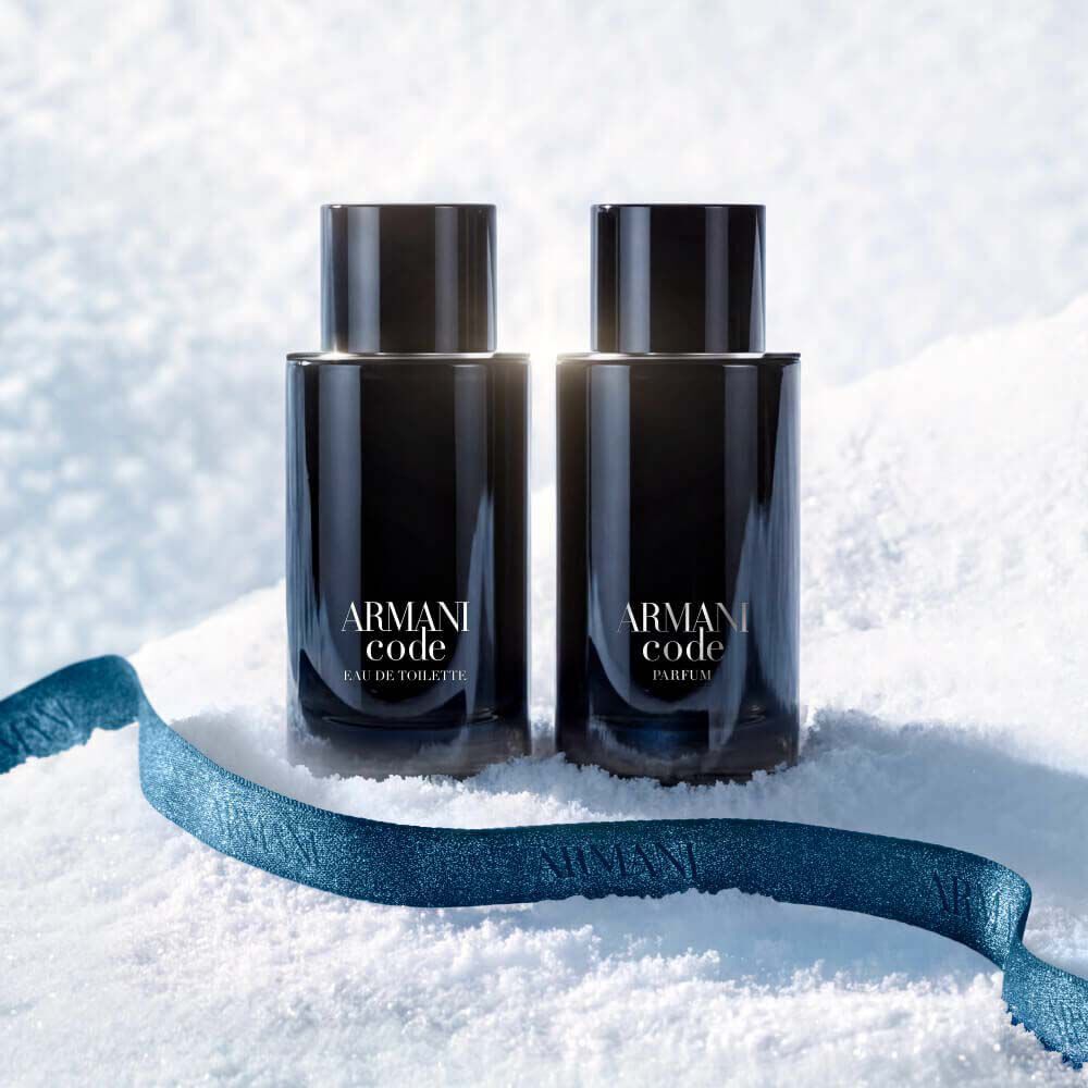 Armani Code Eau de Toilette and Armani Code Parfum black bottles resting in snow with a blue Armani ribbon — Giorgio Armani men's fragrance duo, holiday gifting visual.