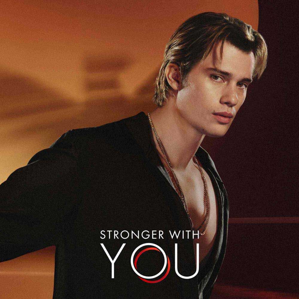 Nicholas Galatzine in black shirt with 'Stronger With You' logo text against warm orange background