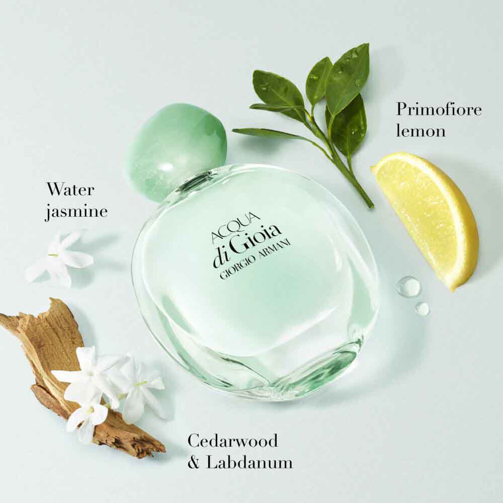Acqua di Gioia Eau de Parfum by Giorgio Armani, mint green bottle surrounded by water jasmine, primofiore lemon, cedarwood and labdanum on a soft aqua background — women's floral aquatic fragrance.