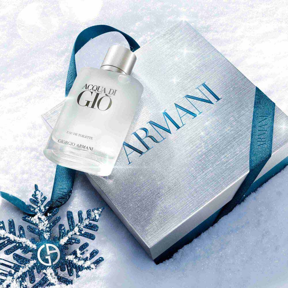 Acqua di Gio Eau de Toilette 50ml gift set in a silver Armani gift box with blue ibbon, styled on a snowy surface with a blue glitter snowflake — Giorgio Armani holiday fragrance gift for men.