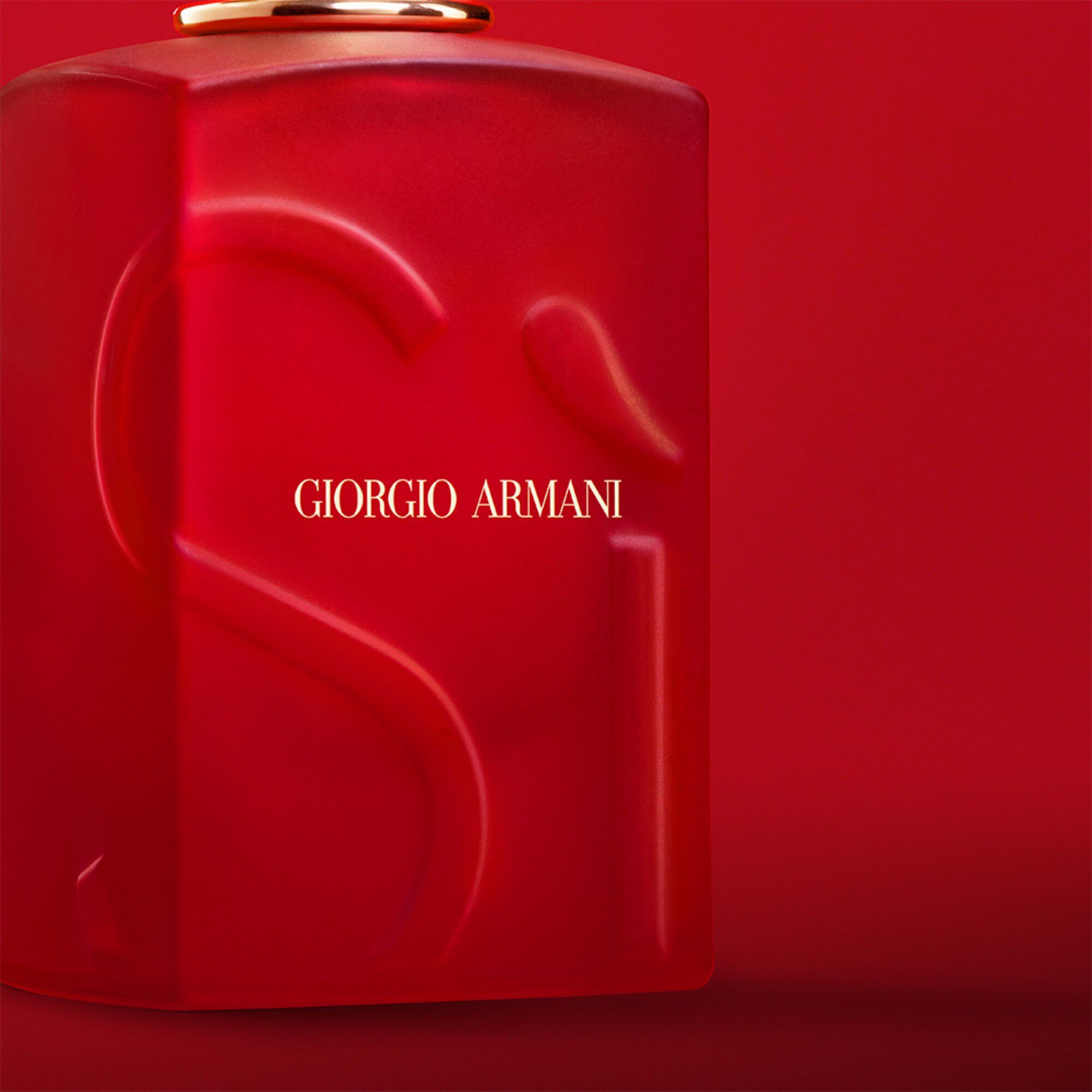 Giorgio Armani Si Passione Red Bloom perfume close up on the bottle on a red background.