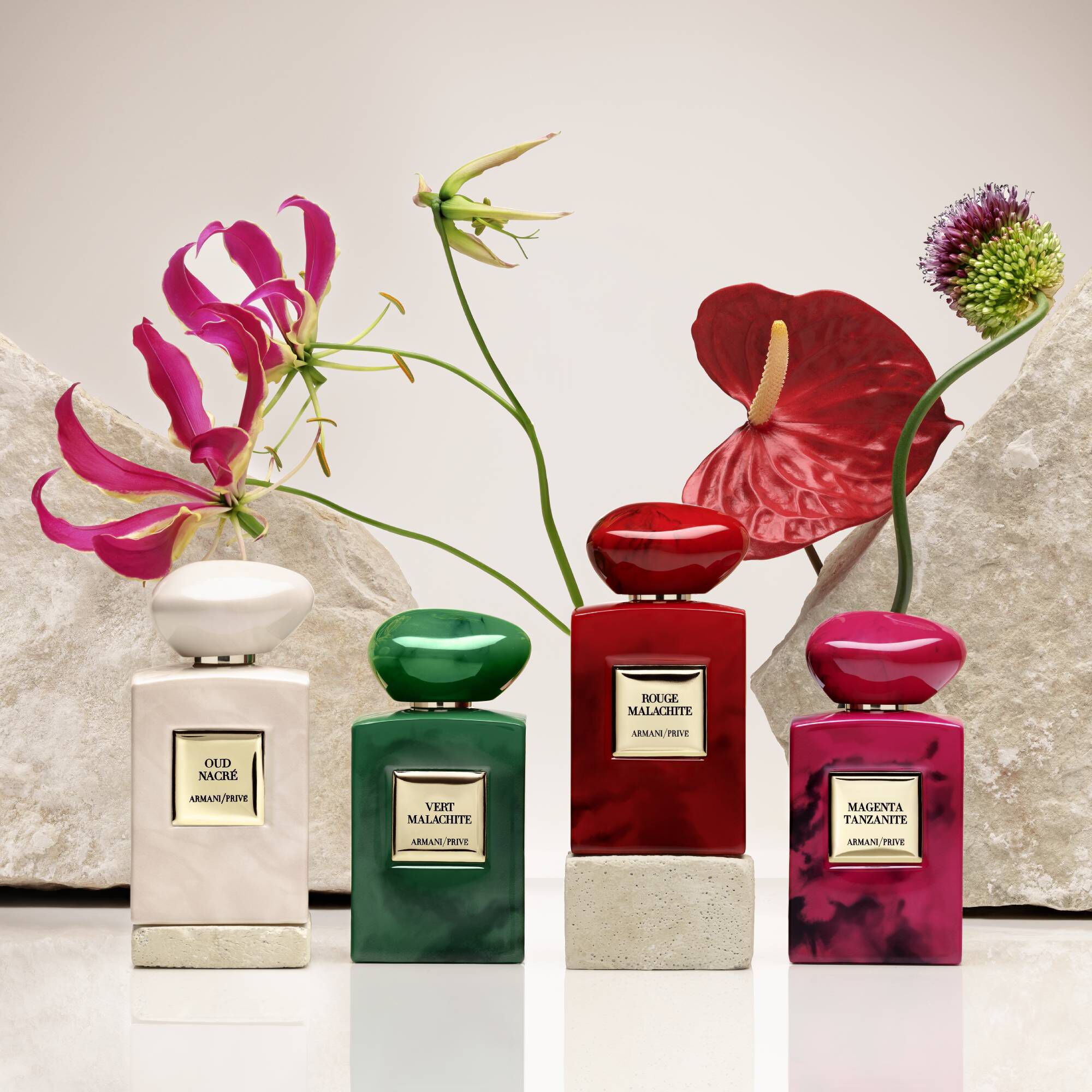 Collection of Armani Prive perfume bottles in various colors with floral accents.